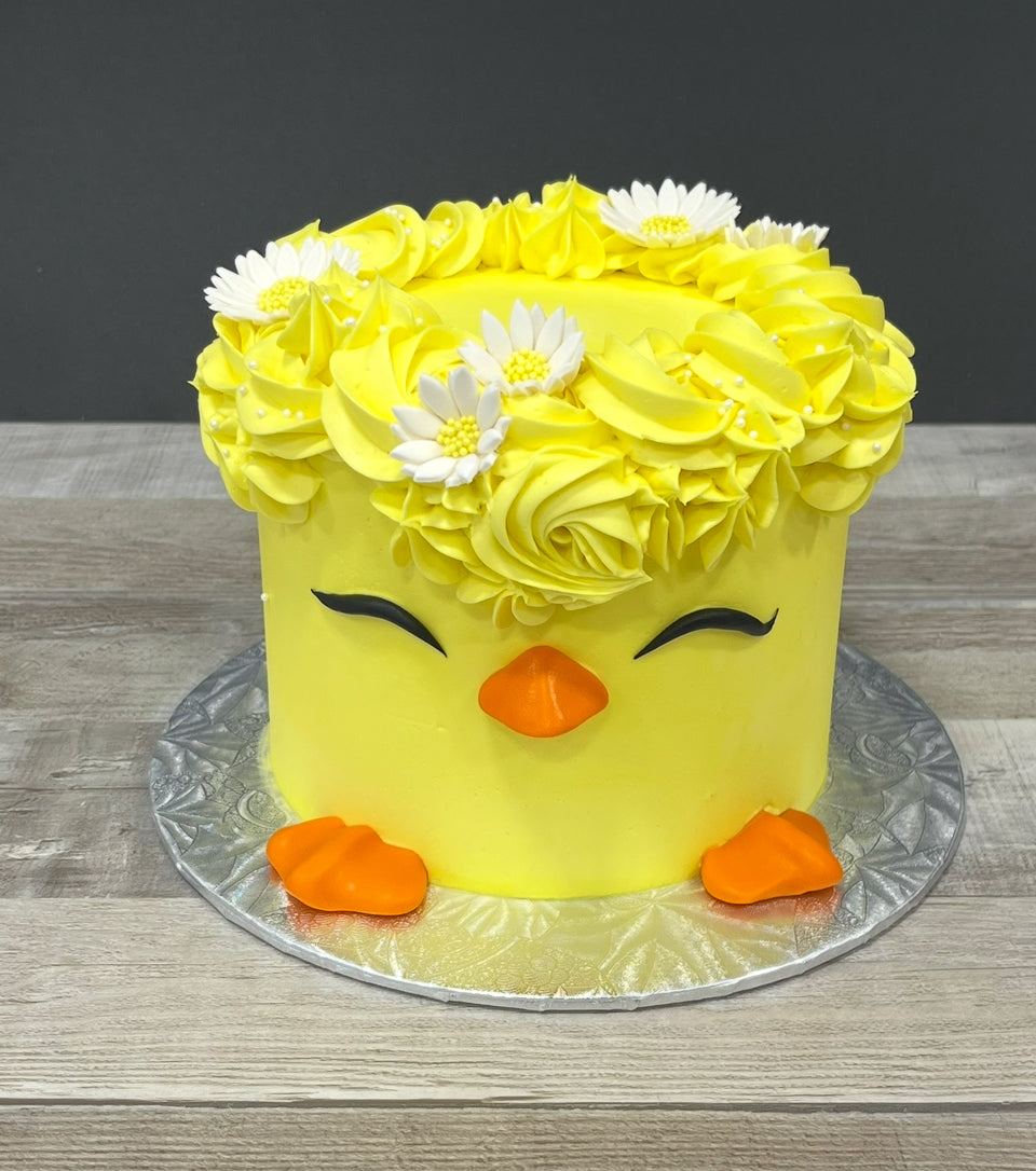 Gâteau en crème au beurre représentant un poussin avec des marguerite dans les cheveux 